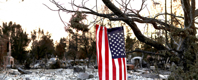 American flag flies over land destroyed by wildfire