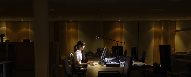 Woman works at computer in dark office