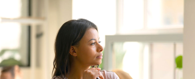 A black female leader looks pensively across an office space