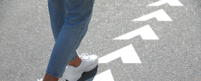 Woman following arrows printed on pavement.