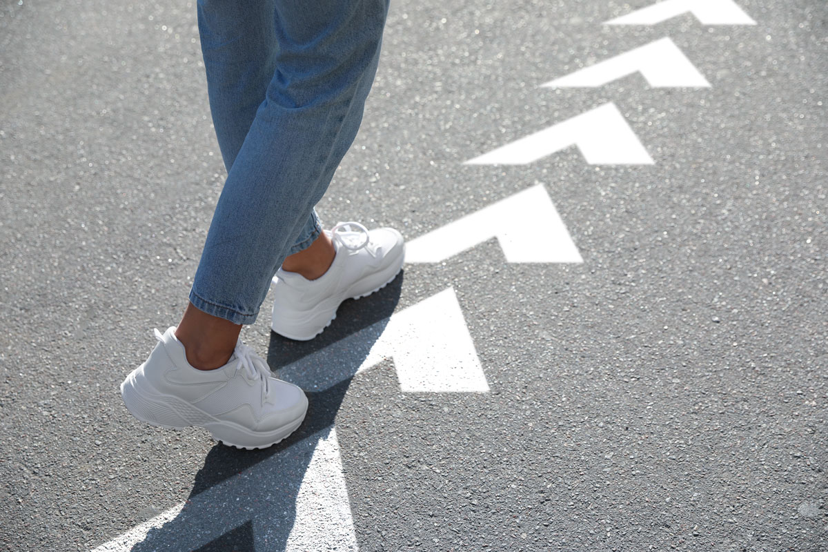 Woman following arrows printed on pavement.