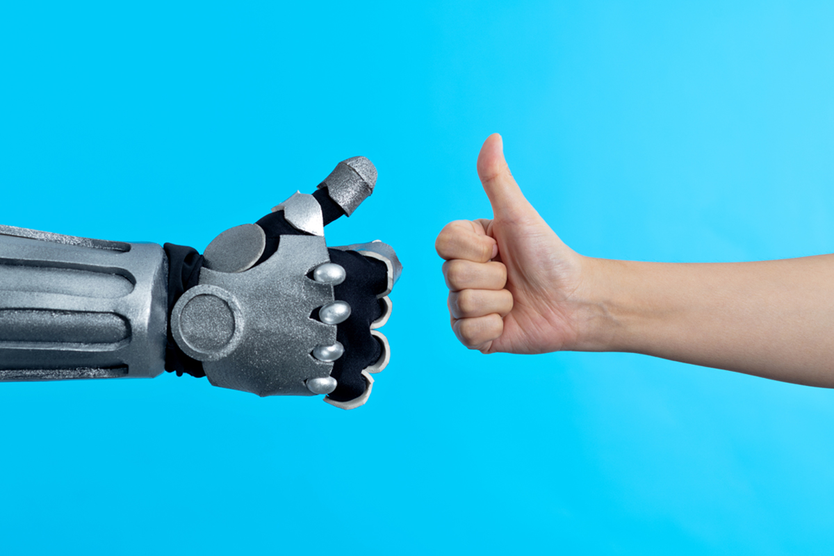 Two hands (one robot and one human) give thumbs up