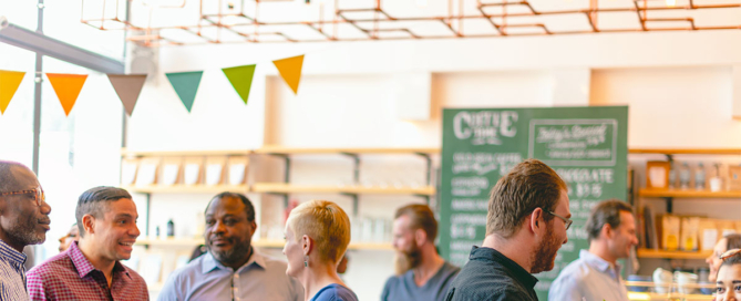 A group of diverse people interact at a coffee shop event.